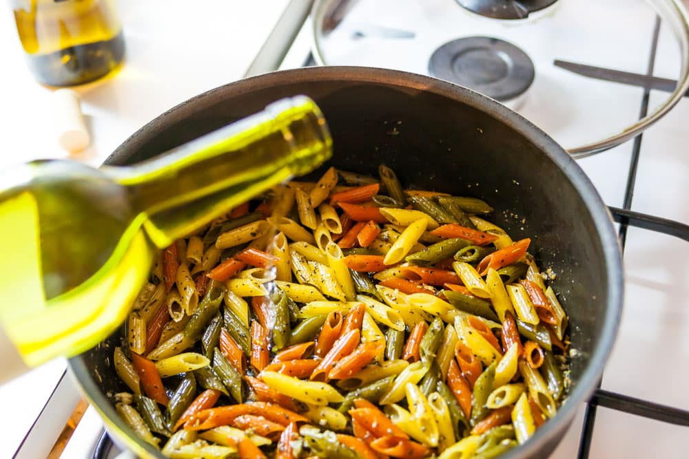 Adding wine in colorful penne pasta in a pan on the stove
