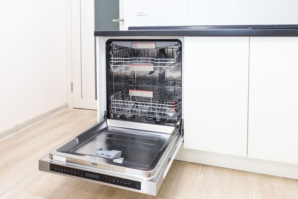 Build-in dishwasher with opened door in a white kitchen