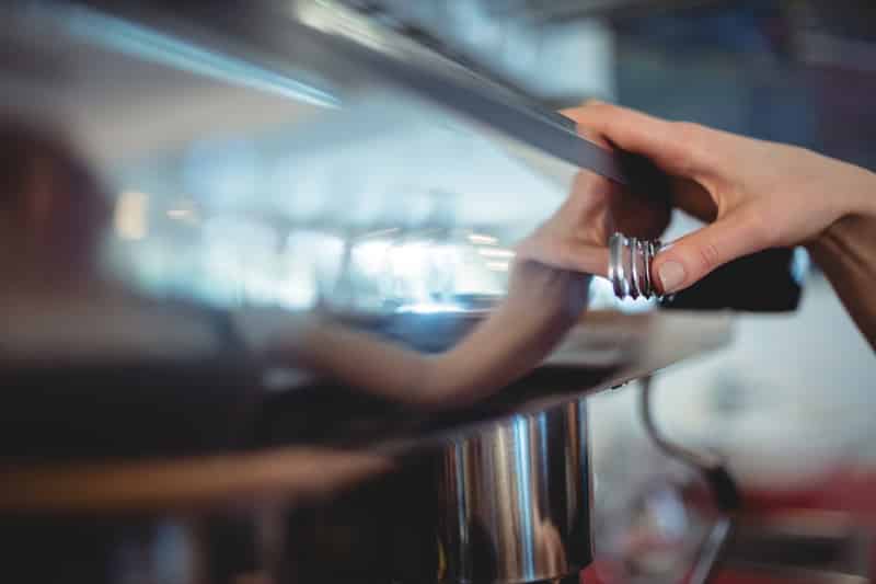 close up barista pushing button coffee maker