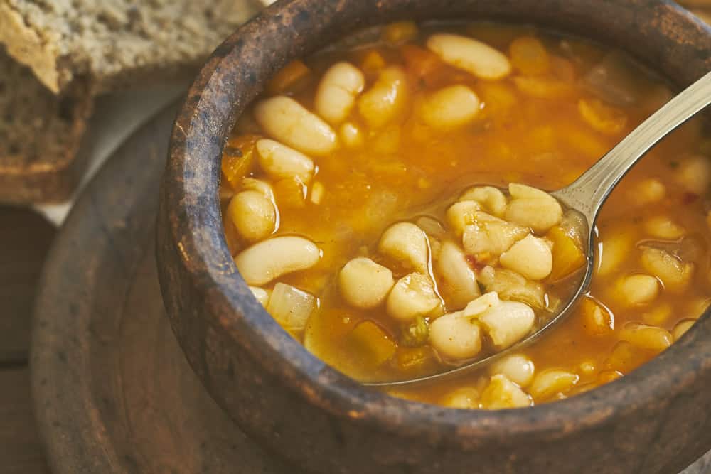 Closeup of cooked beans in clay bowl with spoon