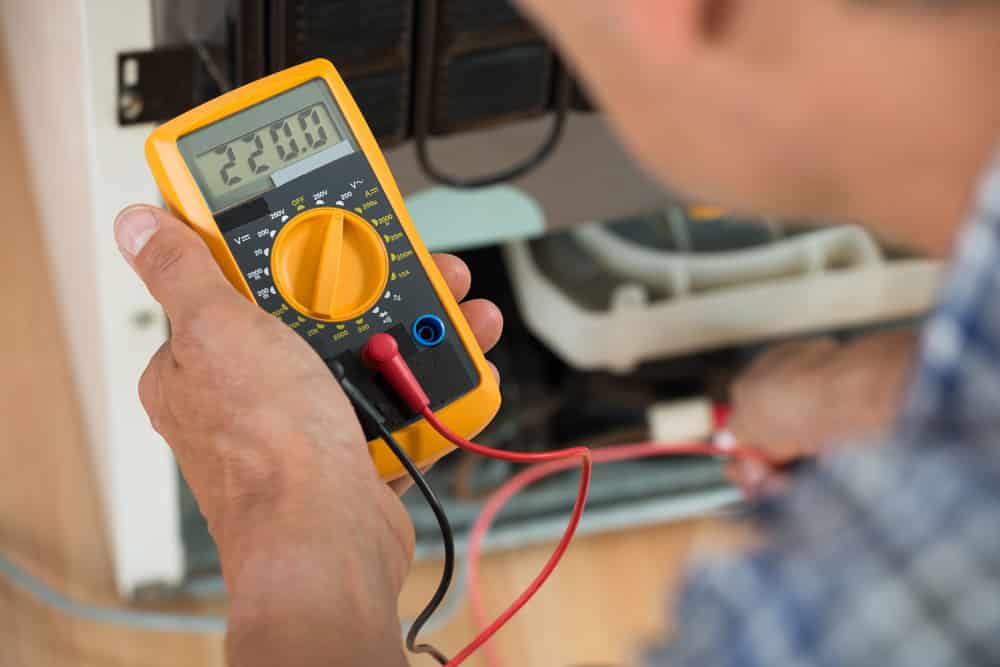 Cropped image of male repairman checking fridge with digital multimeter