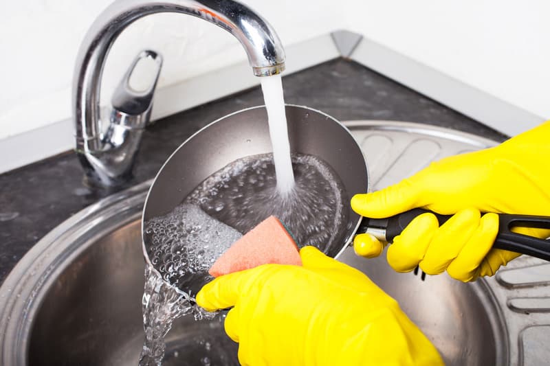 female hands rubber gloves cleaning frying pan kitchen