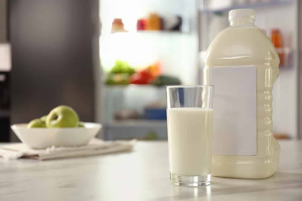 Gallon and glass of milk on table in kitchen