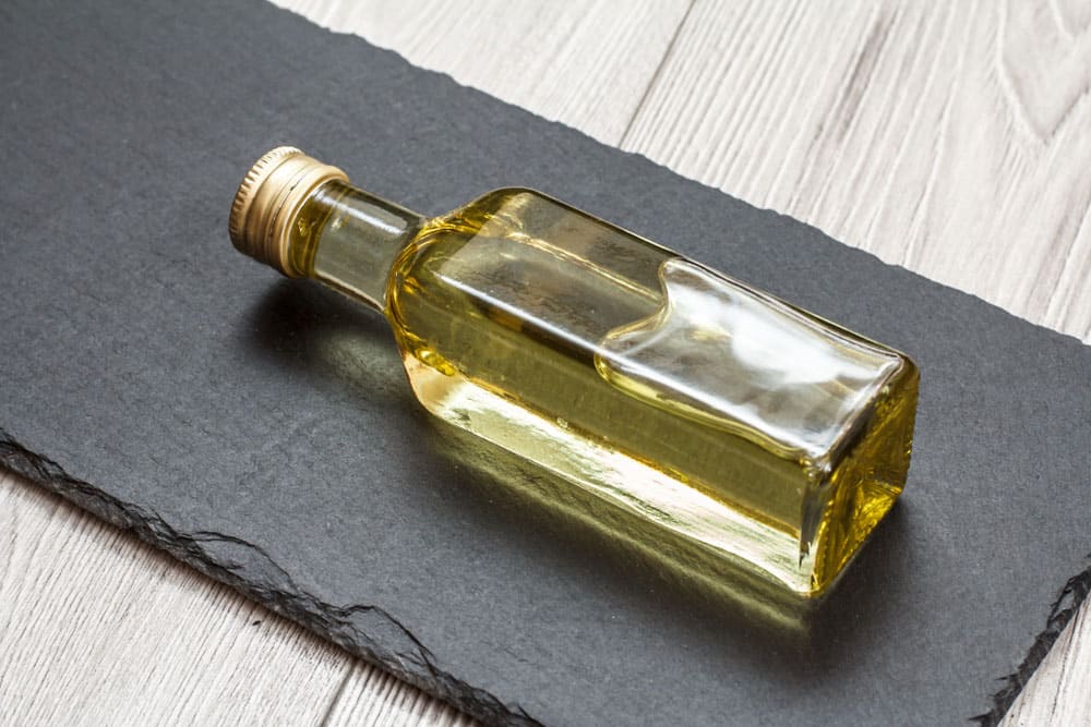 Glass bottle of white cooking wine on black stone board and gray wooden background