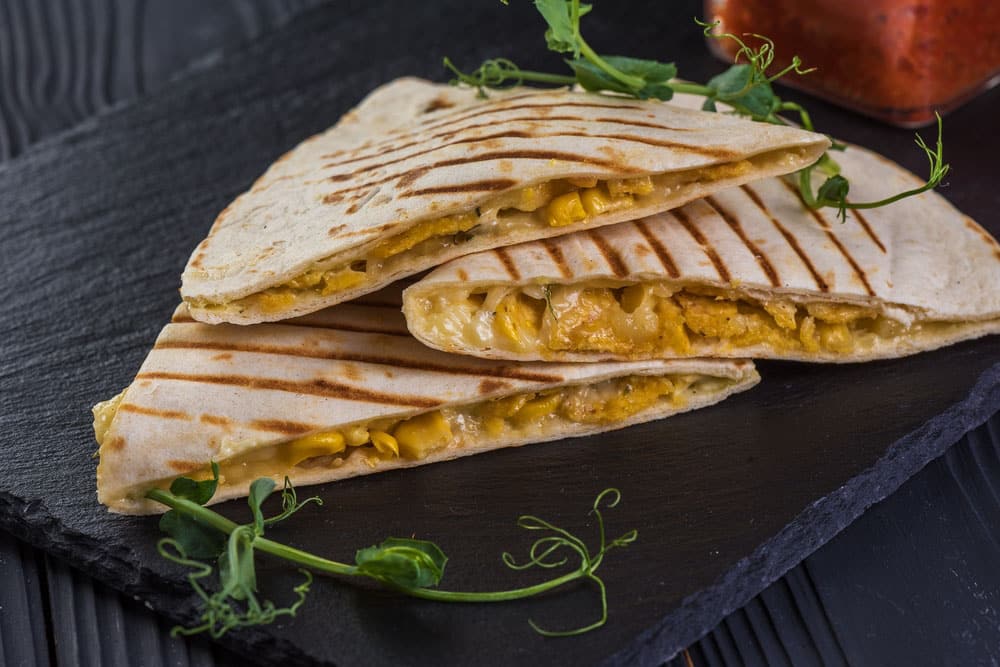 Grilled quesadillas on black wooden background