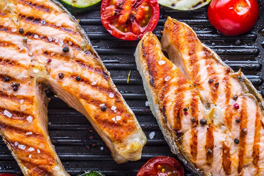 Grilled salmon steak in grill pan with vegetable.