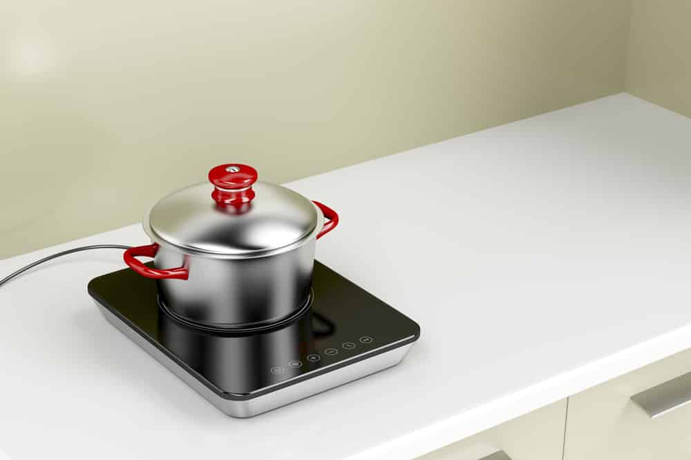 Modern induction cooktop with cooking pot in the kitchen