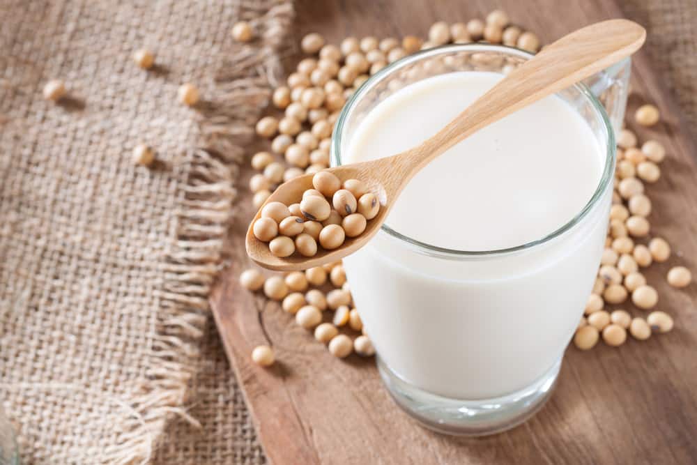 Soy milk on wooden background and sack texture with spoon full of soybeans