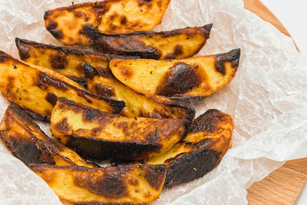 overcooked burnt potatoes on a wooden board and baking paper