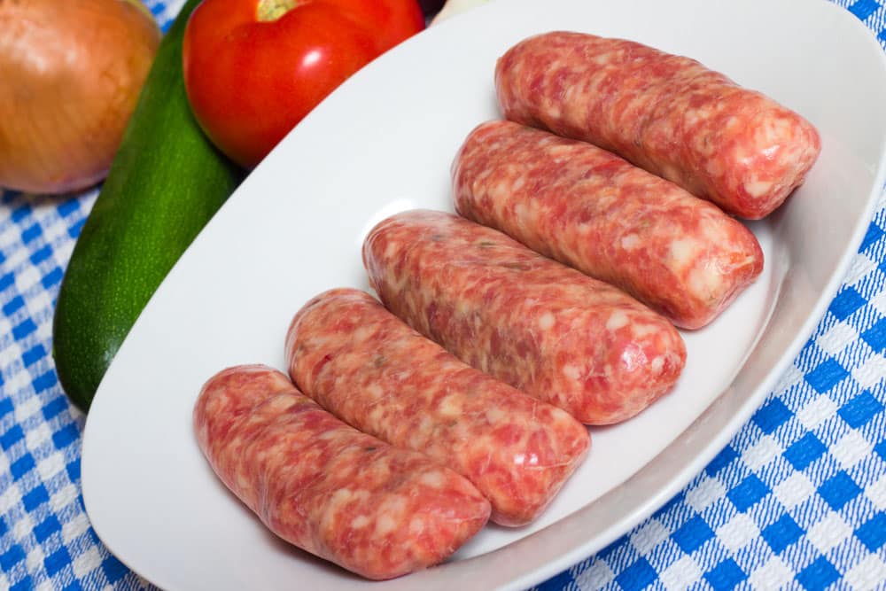 Uncooked sweet Italian sausage on a plate ready to be cooked
