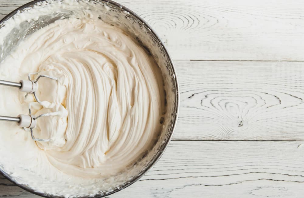 White butter cream in a metal bowl. Beating cream cake