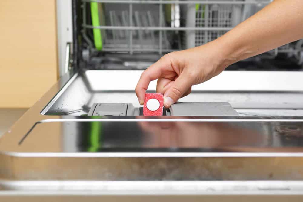 Woman putting tablet in dishwasher detergent box