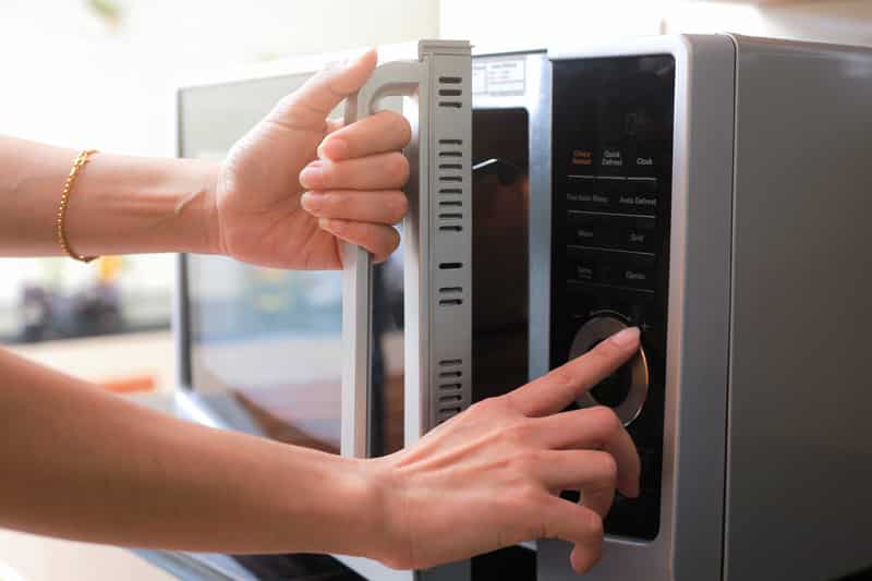 woman's hands closing microwave door