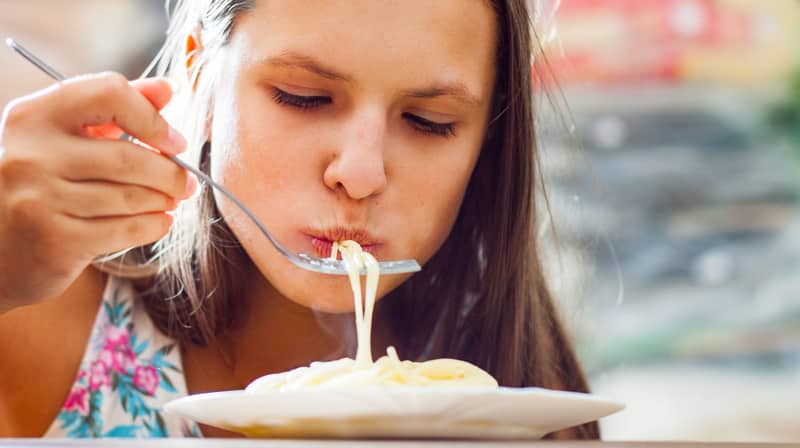young teenager girl eating spaghetti pasta