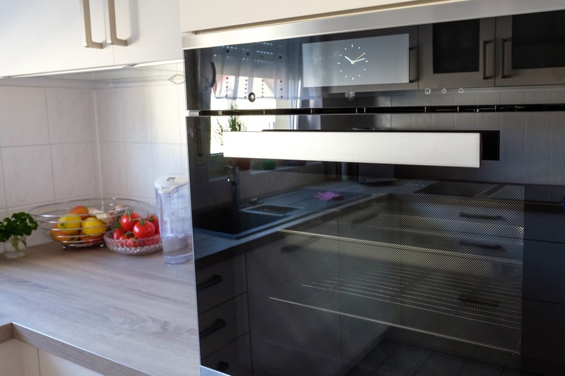 Baking oven with steam cooker and kitchen with worktop