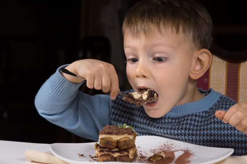 Cute little boy eating chocolate cake