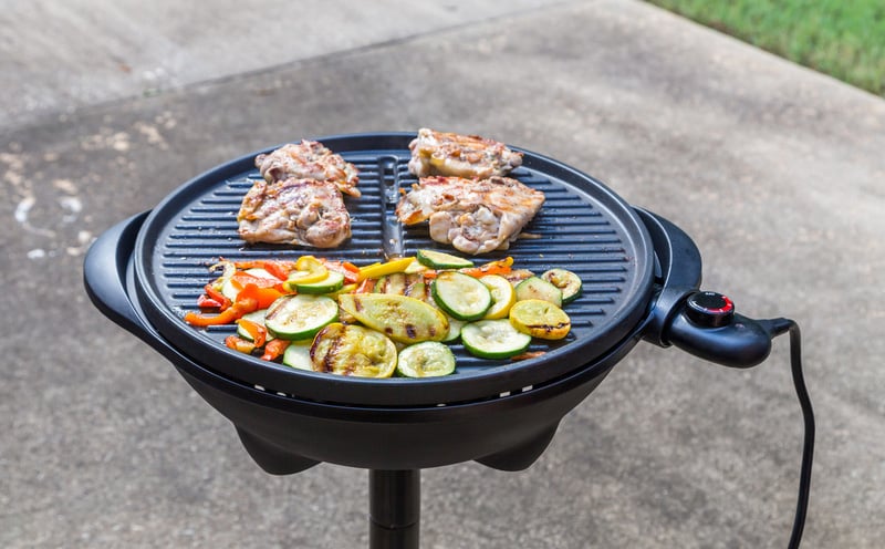 Assorted grilled vegetables and chicken thighs on an electric grill