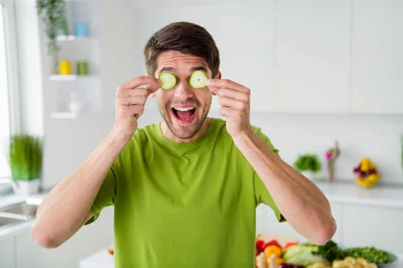 man cooling eyes with cucumbers