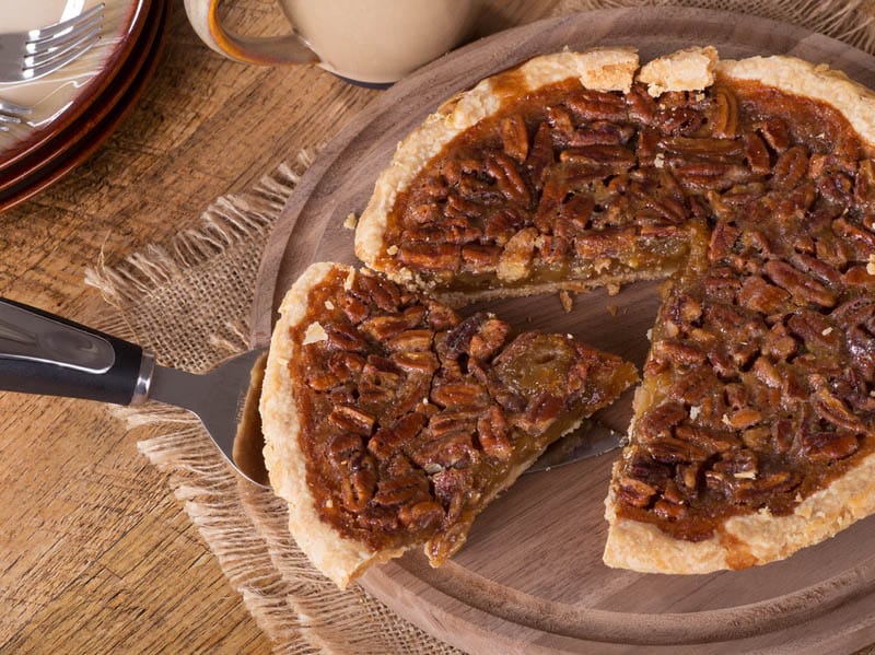 Overhead of a slice of pecan pie on a wooden platter