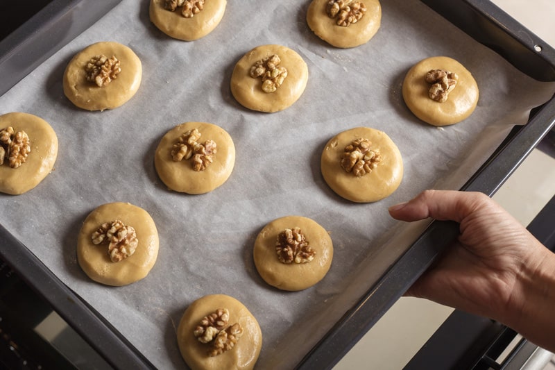 Raw honey biscuits with walnuts on a baking sheet with parchment paper