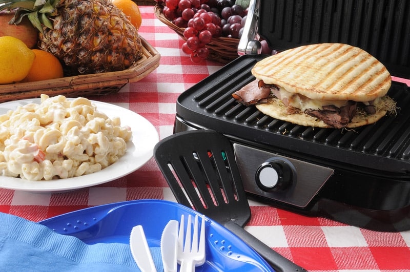 A roast beef and swiss cheese panini being grilled on a picnic table