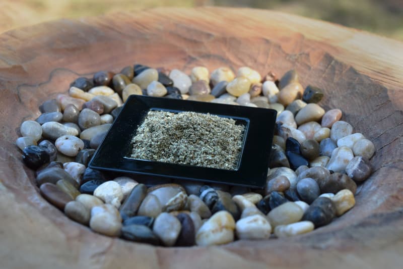 This is a picture of a small square black dish of rubbed sage