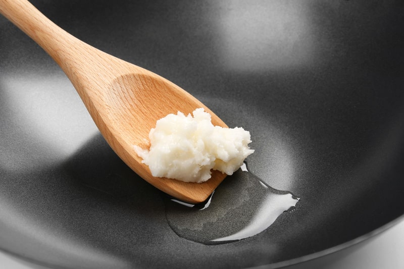 Spatula with coconut oil in wok