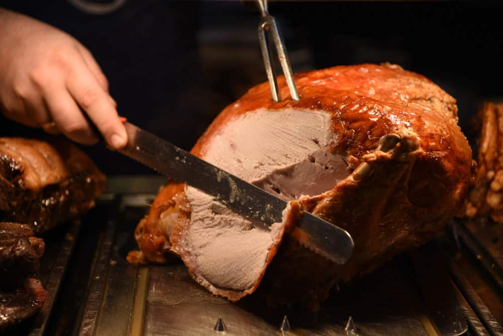 succulent roast turkey with hand and a knife carving the meat