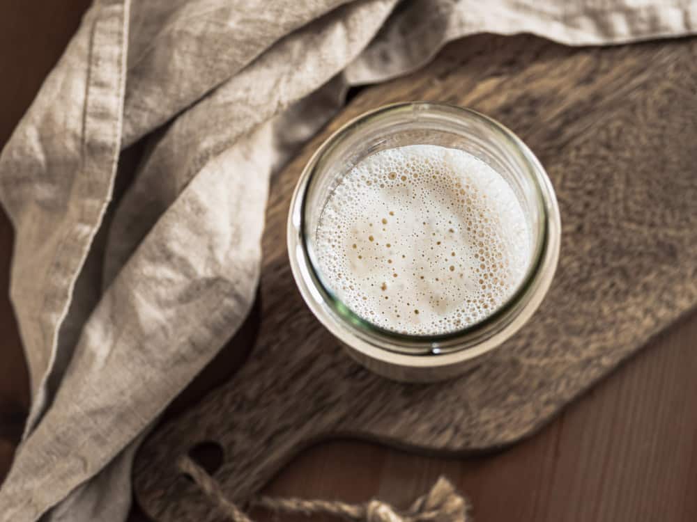 Top view of glass jar with sourdough starter on wooden cutting board