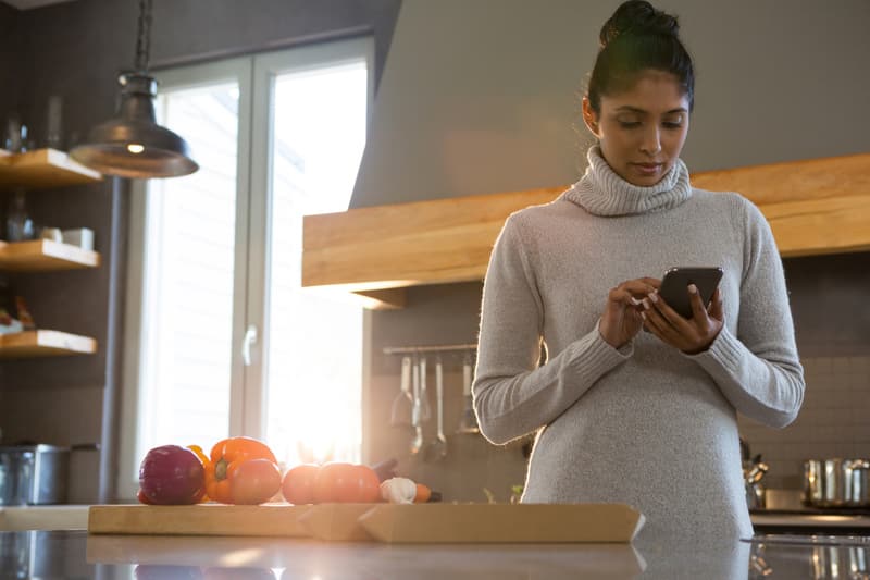 Woman using phone in kitchen