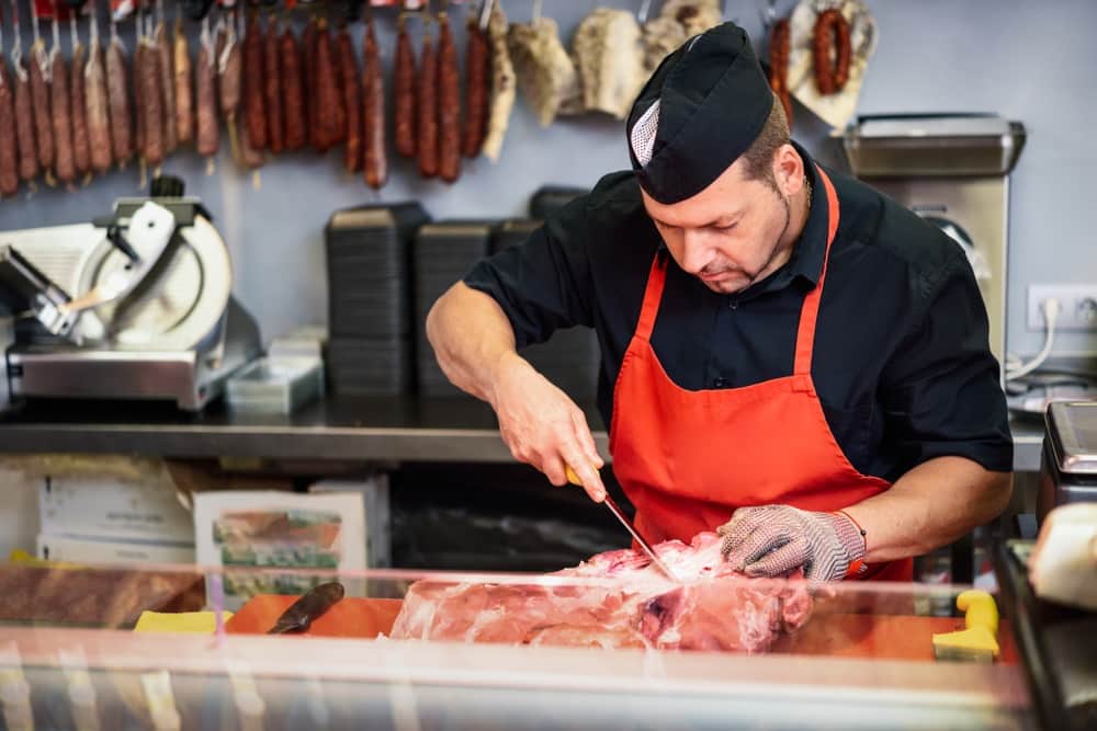 Male butcher boning fresh ham