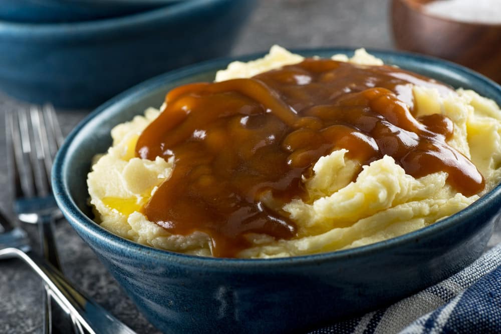 A bowl of delicious mashed potatoes with gravy and melted butter