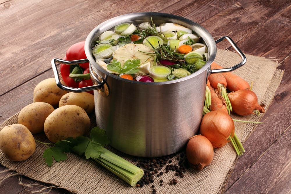 Broth with carrots onions various fresh vegetables in a pot