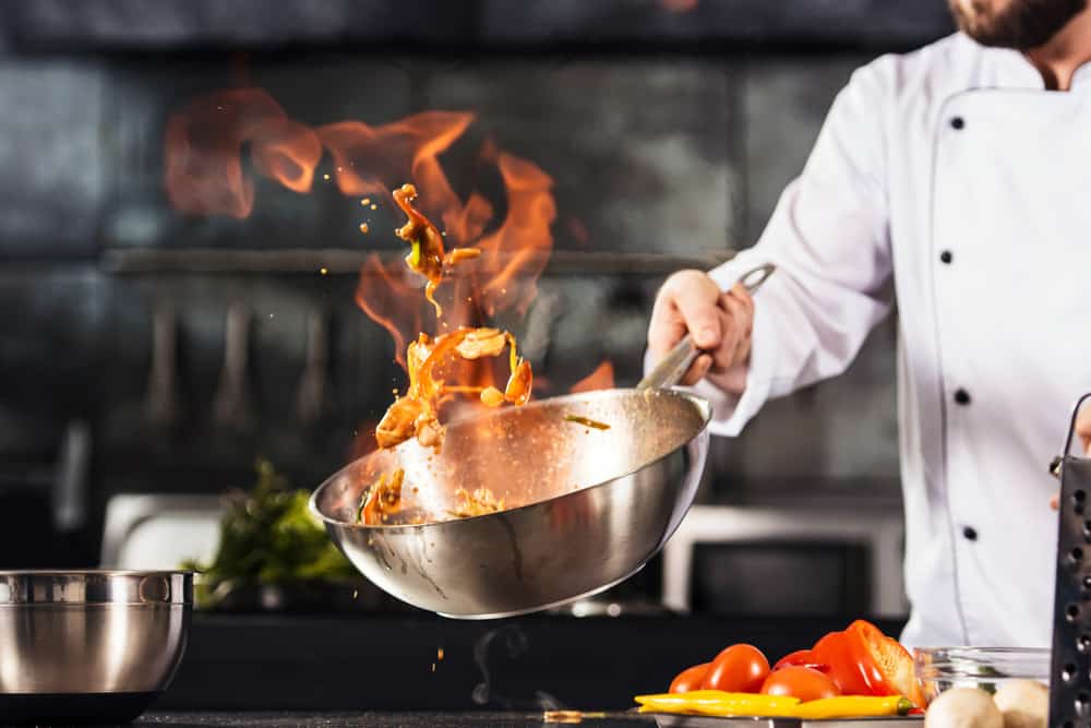 Chef hands keep wok with fire