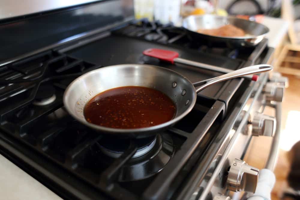 Demi glace or brown glaze cooking in a stainless steel skillet 