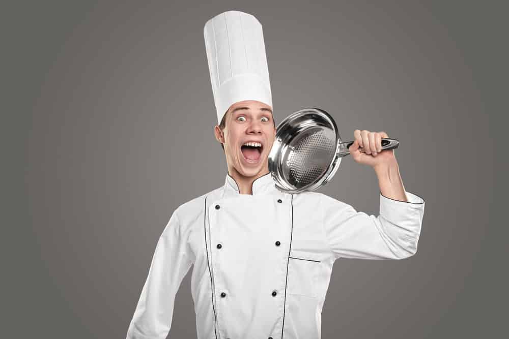 Funny young male cook in white uniform and hat screaming happily