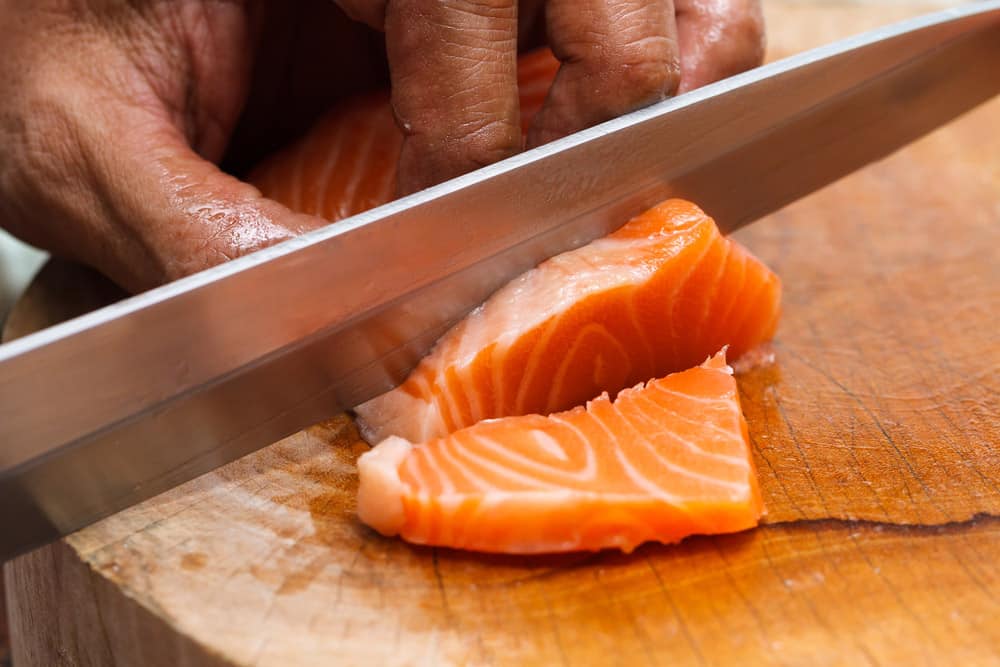 Hand and fingers Japanese chef use sharp knife slicing fresh salmon