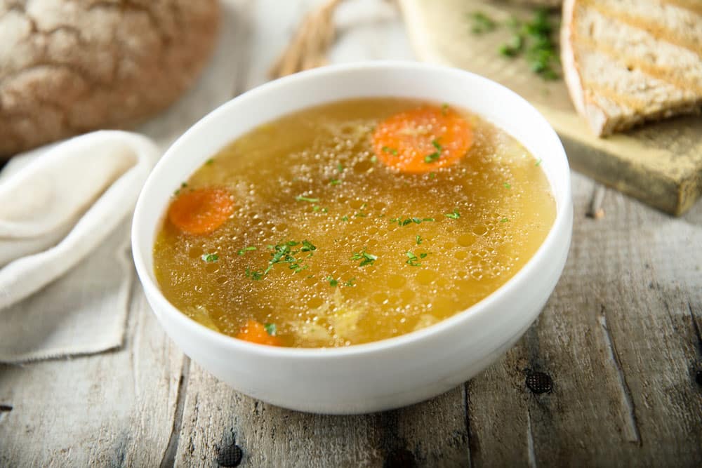 Homemade chicken broth in white bowl