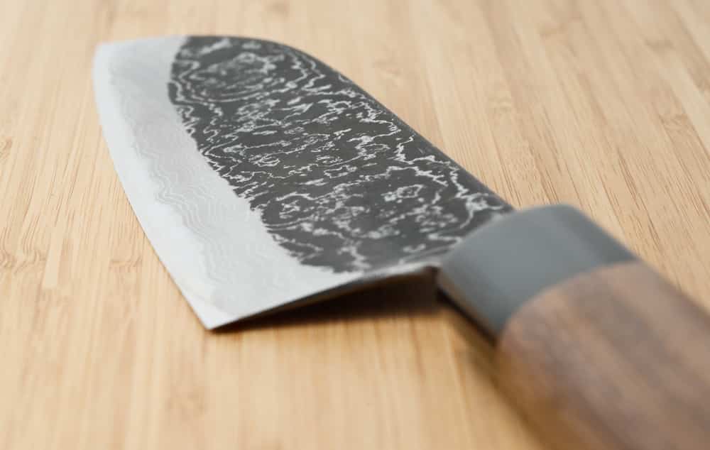 Japanese damascus carbon steel knife on wooden plank