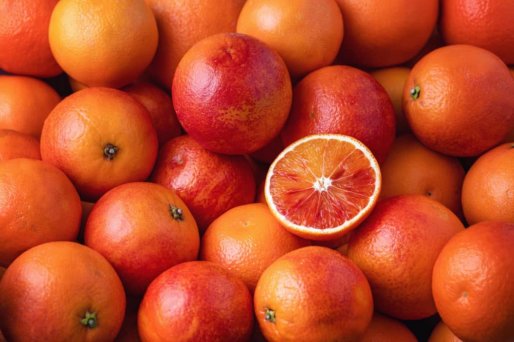 Many blood oranges, whole and halved