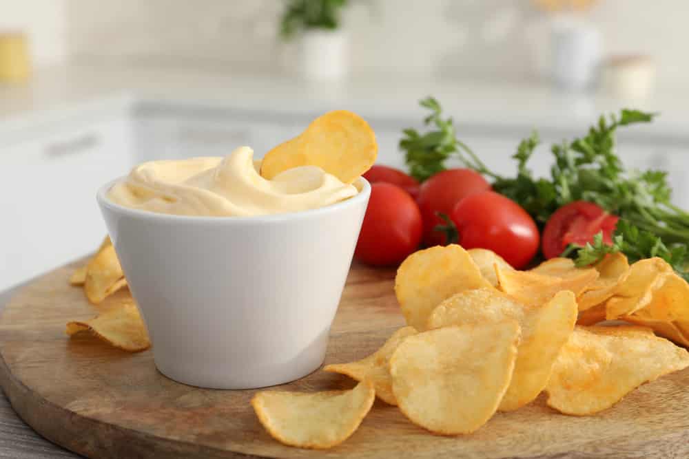 Potato chips and mayonnaise on wooden board