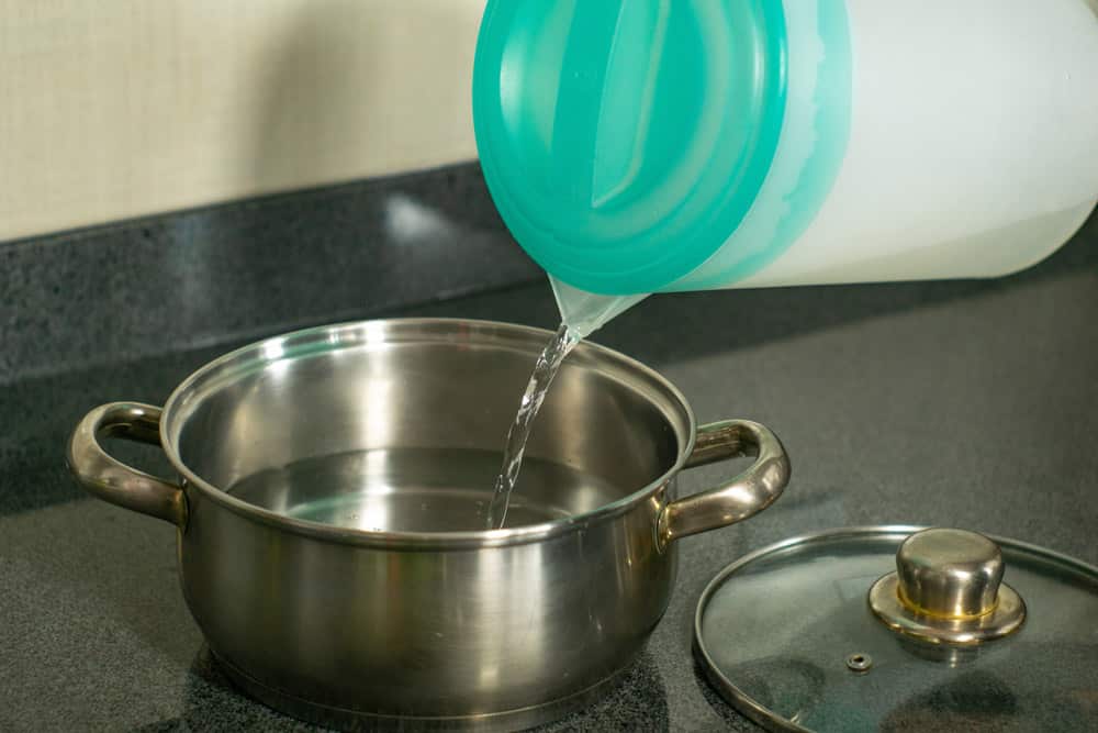 pouring water from jug in cooking pot