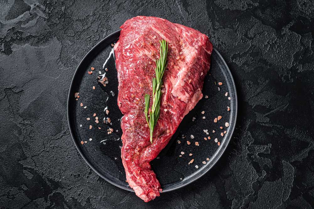 Seasoned raw tri-tip beef meat steak on plate