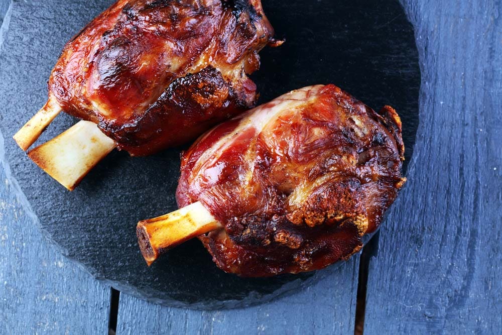 Smoked ham hock with herbs and spices on wooden plate