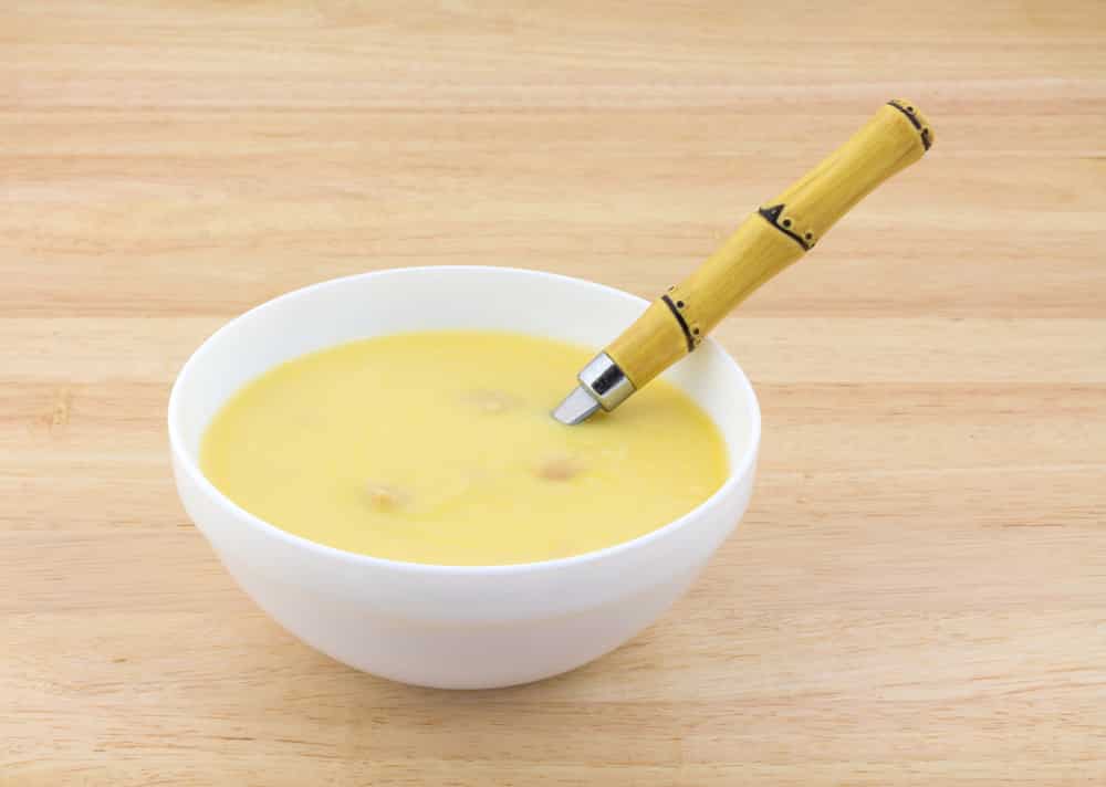 A white bowl filled with chicken soup and spoon