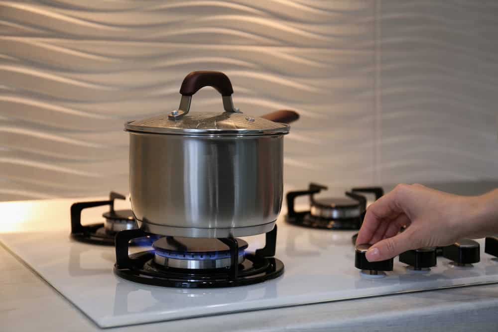 Woman cooking food in pot on modern kitchen stove