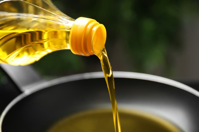 Pouring cooking oil from bottle into frying pan