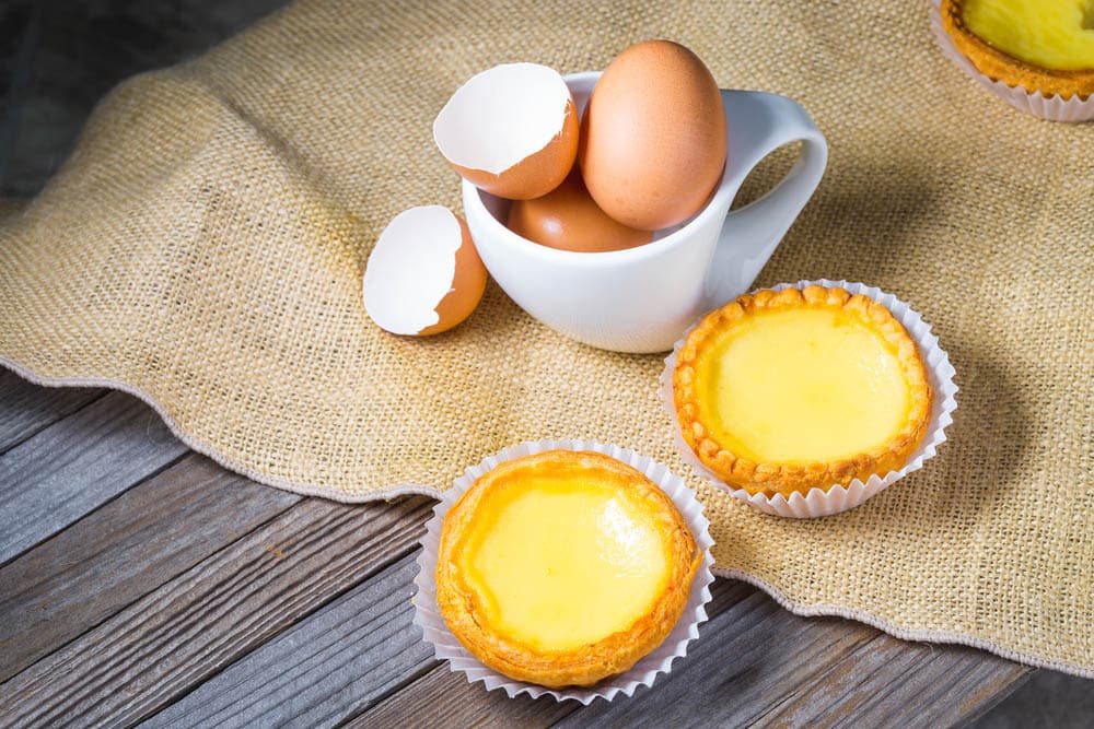 Delicious freshly baked egg tarts on wooden background