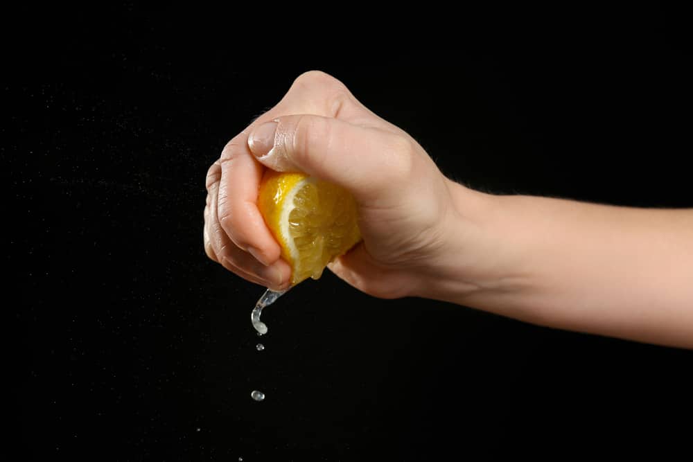 Female hand squeezing half of lemon