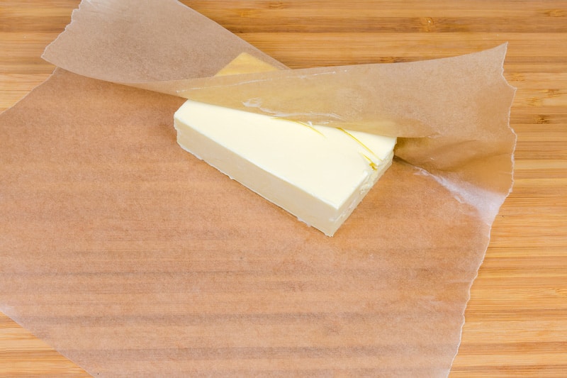 Piece of butter in waxed paper on a wooden surface